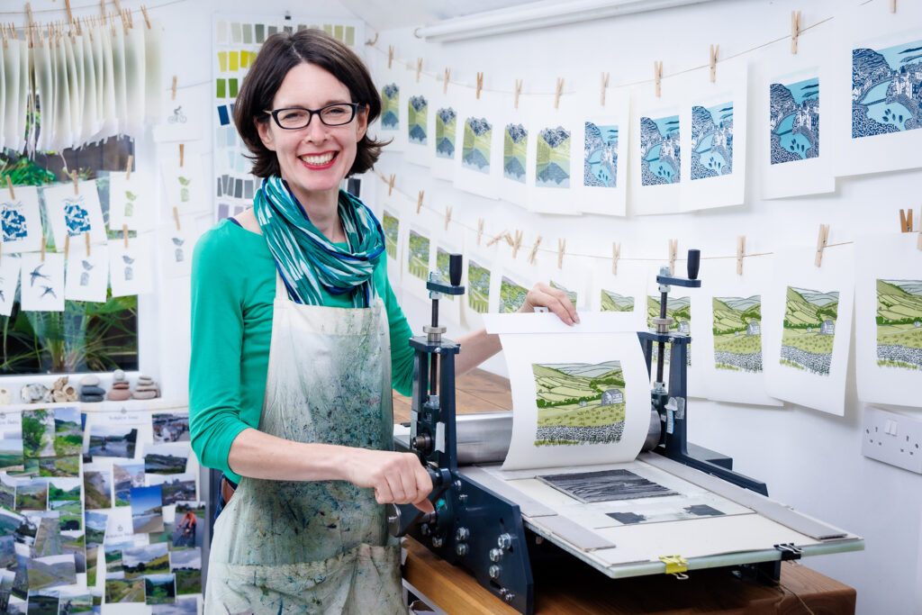 Michelle Hughes Yorkshire landscape artist with linocut prints drying behind her