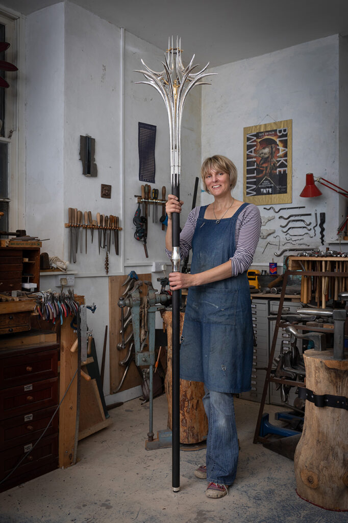 Rauni Higson standing with Liverpool Met Cathedral Processional Cross